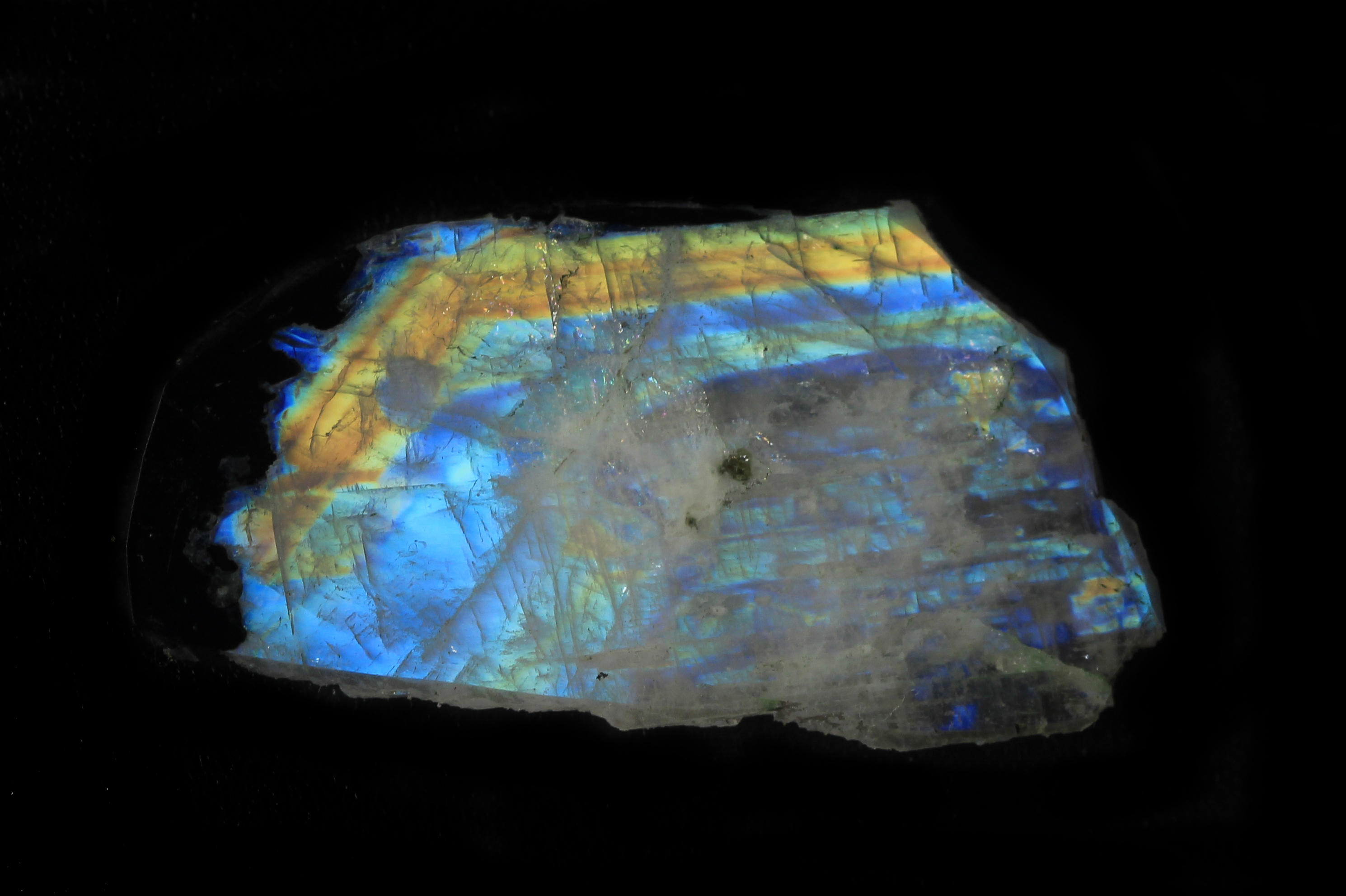 A photograph of labradorite: blue, turquoise, and gold light across the natural mineral’s surface.